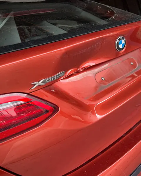 BMW 2 Series tailgate before repair, creased beside the xDrive badge